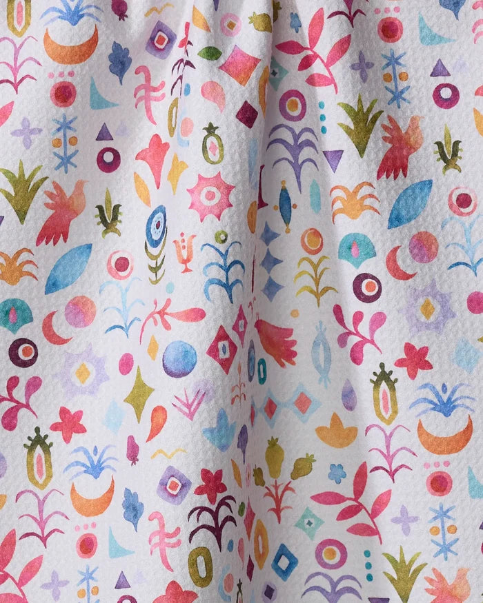 Tula by Maayan Alper-Swan features a whimsical pattern of abstract shapes, flowers, leaves, birds, and geometric forms in pink, blue, green, and yellow on a textured white ultra-absorbent tea towel made from recycled materials.