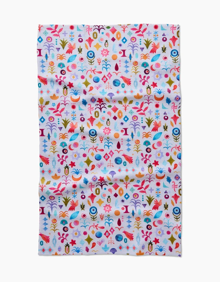 The Tula Tea Towel by Maayan Alper-Swan showcases a vibrant abstract floral and geometric pattern in red, blue, yellow, orange, and pink on white Geoweave fabric that is soft and eco-friendly.