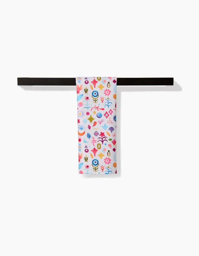 The Tula bar towel by Maayan Alper-Swan, made from recycled materials and decorated with abstract floral patterns, hangs neatly on a dark towel bar against a white background.