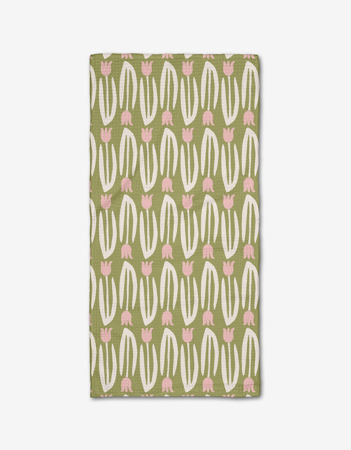 Kayla Anns Tulip Tango Bar Towel is rectangular, made from recycled materials, and features a playful modern pattern of white curved lines and pink tulip-like shapes in vertical rows on a solid green background.