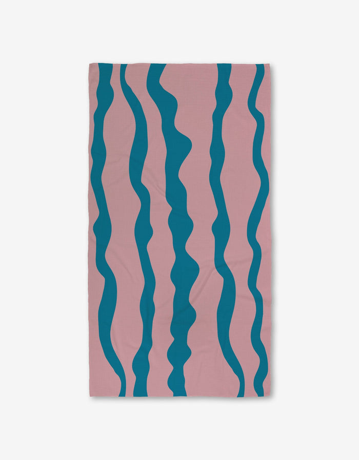 The GEOMETRY Turquoise Twist towel features a pink base with five wavy blue stripes and Geoweave technology, offering ultra-absorbency for those seeking stylish and functional Luxe Bath Towels.