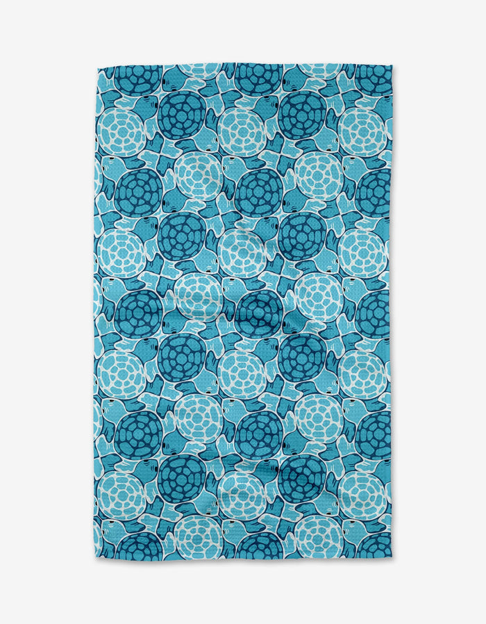 The Turtles tea towel by Marta Harvey is a rectangular blue towel made from recycled materials, featuring a close pattern of stylized sea turtles in blue shades.
