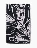 The Ash Cascade Twilight Plant is a rectangular black kitchen towel with abstract white floral and leaf patterns. Bold lines and stylized shapes create a modern, eco-friendly accent for any space.