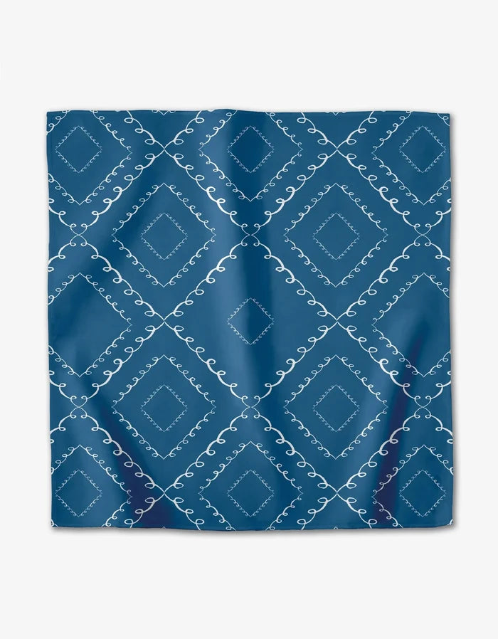 The Elena Fay Twirls set features blue square dinner napkins with a white diamond and swirl pattern in a repeating grid. These absorbent cloth napkins offer a smooth, lightly shiny finish perfect for elegant dining.