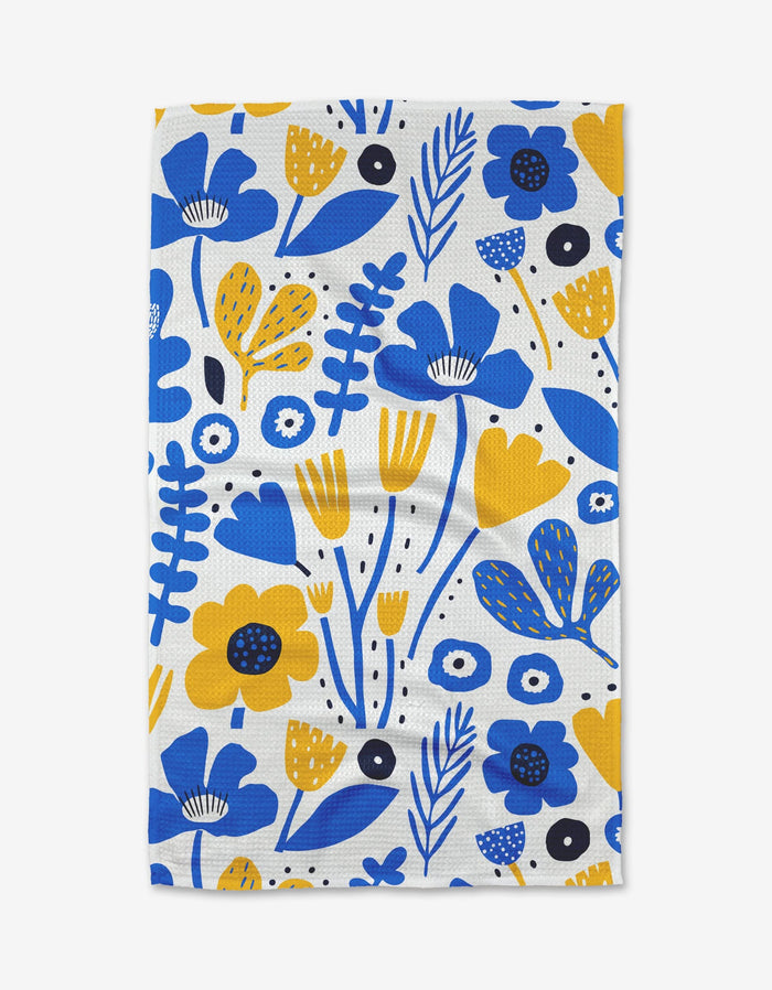 The Ukrainian Florals tea towel by Marina Solodka features blue and yellow flowers with leaves and abstract shapes on white, crafted from recycled materials.