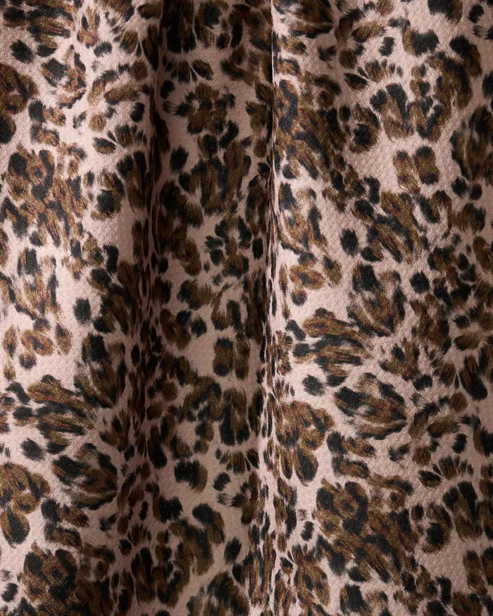 A close-up of Geometrys Umber dish towel, featuring an absorbent fabric with a leopard print in brown, black, and beige. Dark, irregular spots stand out on a light background with visible folds and textured detail.