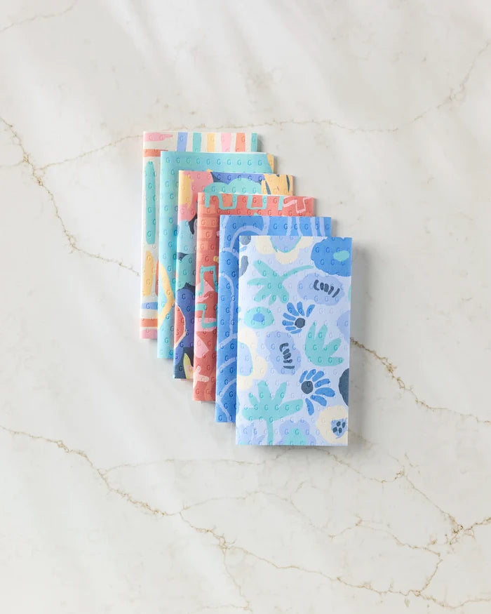 Five eco-friendly, reusable kitchen towels from Sareka Unique are stacked on a white marble surface. The Unique towels feature playful blue, green, and pink patterns—an ideal alternative to disposable paper towels.