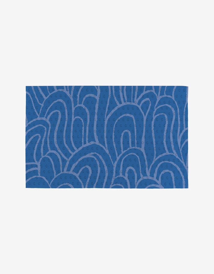 The Sareka Unique Unique towel is a blue rectangle with an abstract pattern of curving lines and small dots in lighter blue on a plain white background, made from eco-friendly post-consumer recycled materials.
