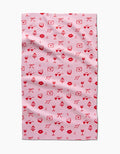 The V Day Doodles tea towel by Laura Supnik is made from recycled materials and features a playful, romantic design with red and pink icons like lips, hearts, envelopes, bows, leaves, wine glasses, and flowers.