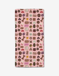 The Elisabeth Wing “Valentine’s Chocolates” Bar Towel features a pink background with a colorful pattern of assorted chocolates and candies. Made from Geoweave fabric, the rectangular towel is shown flat on a white surface.