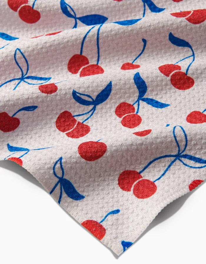 The Kayla Ann Very Cherry bar towel is made from white Geoweave fabric and features a textured surface with evenly scattered red cherries and blue stems and leaves.