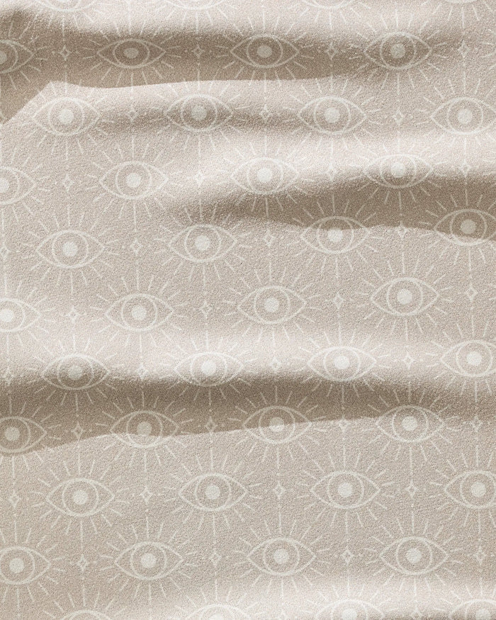 The Geometry Vision towel is a beige, ultra-absorbent fitness towel featuring a mystical repeating eye pattern with ray-like lines and gentle waves for texture. Quick-drying fabric ensures style and performance.