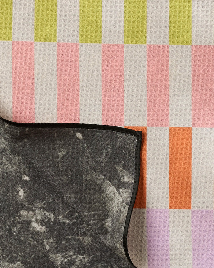The Geometry Wag Wise mat is made from recycled materials and features a pastel green, pink, orange, and white checkered pattern with a marbled underside and black edge—perfect as a sustainable, stylish dog towel.
