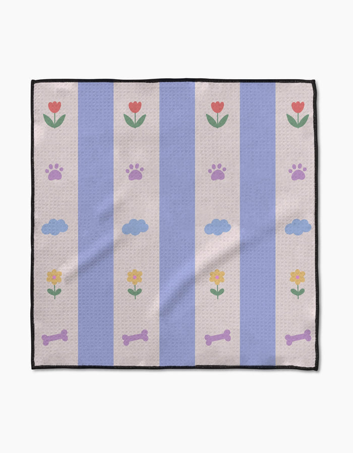 The Wagging Blooms pet towel by Letters By Shells features vertical light blue and beige stripes with red and yellow flowers, purple paw prints, blue clouds, and purple dog bones—ultra-absorbent and perfect for your furry friend.