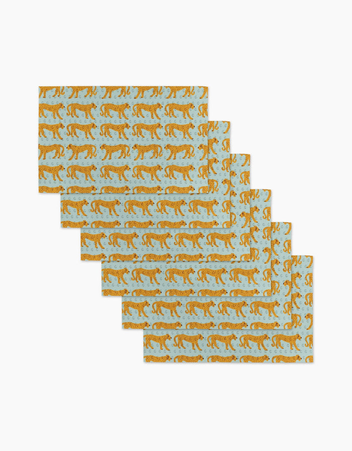 Six Walking Cheetah rectangular placemats by Jasmine Blooms Designs, featuring orange cheetahs on light blue, made from post-consumer recycled materials, are displayed in a fanned-out stack on a white surface.