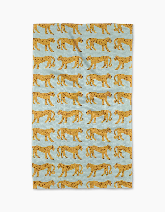 The Walking Cheetah tea towel by Jasmine Blooms Designs features a light blue background with a repeating pattern of stylized yellow cheetahs with black spots walking in alternating directions.