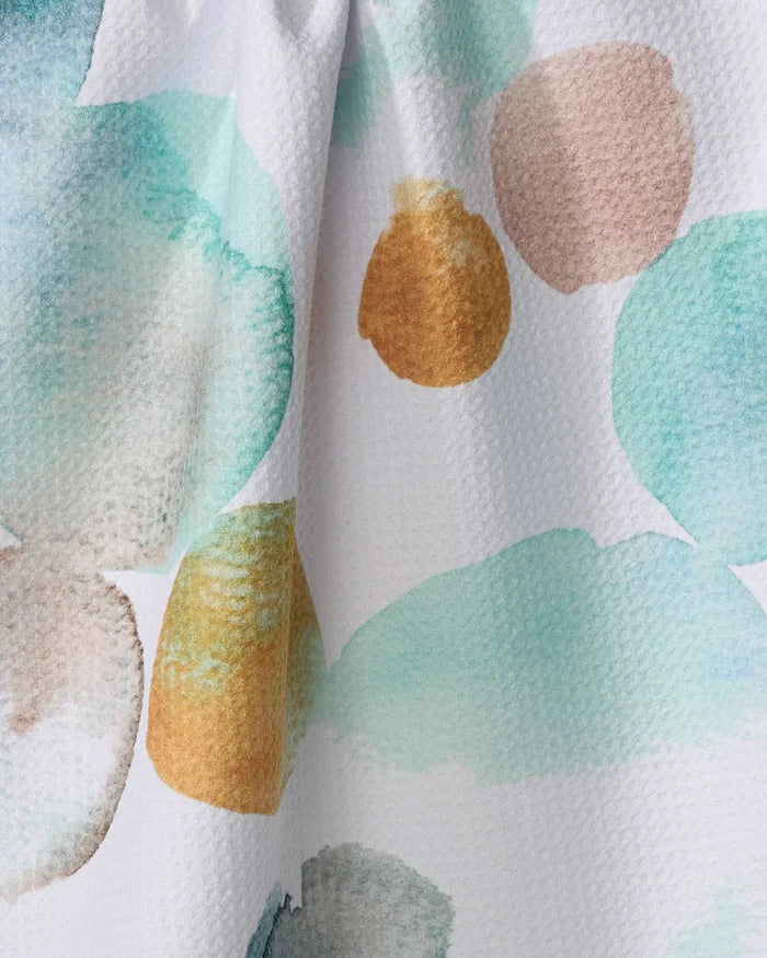 Close-up of Watercolor Rocks by Taryn Brennan—a textured white fabric featuring teal, light brown, and gold abstract spots, perfect for a quick-drying tea towel crafted from recycled materials.