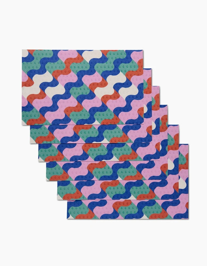 Six reusable Wavy Stripes cloths by Claire Iglesias, featuring blue, red, green, pink, and white abstract wave patterns, are stacked on a white background—an eco-friendly alternative to paper towels.
