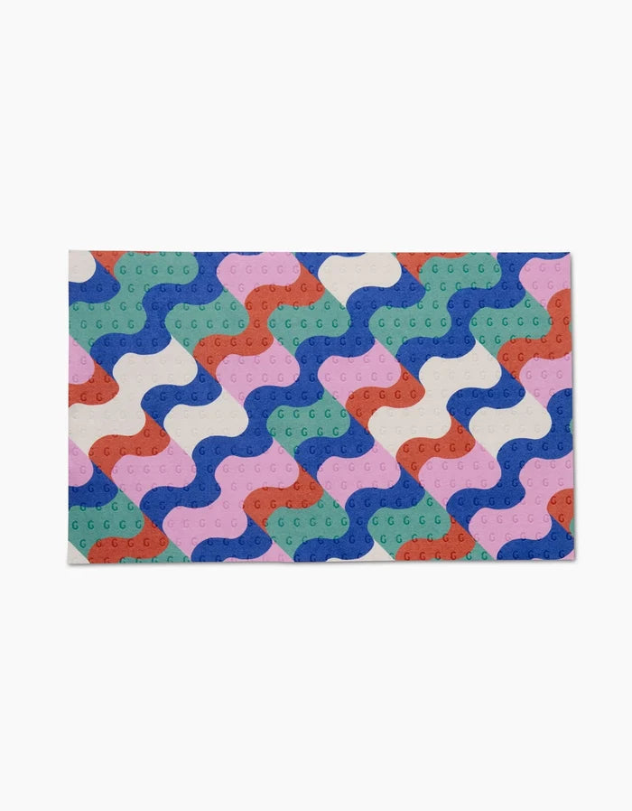 Claire Iglesias Wavy Stripes mat features interlocking wavy patterns in blue, green, red, pink, and white with small circles. Reusable and eco-friendly, its the ideal sustainable alternative to paper towels.