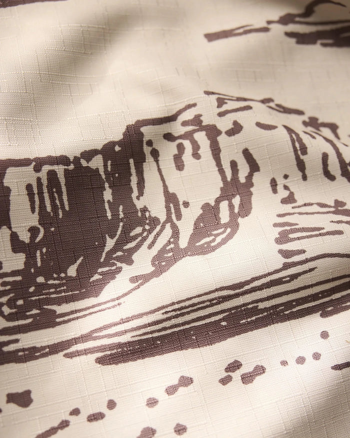 The Geometry Western Scene features a close-up of beige fabric with a brown landscape print of abstract rock formations and textured grids—ideal as a lightweight tablecloth for adding subtle, artistic style.