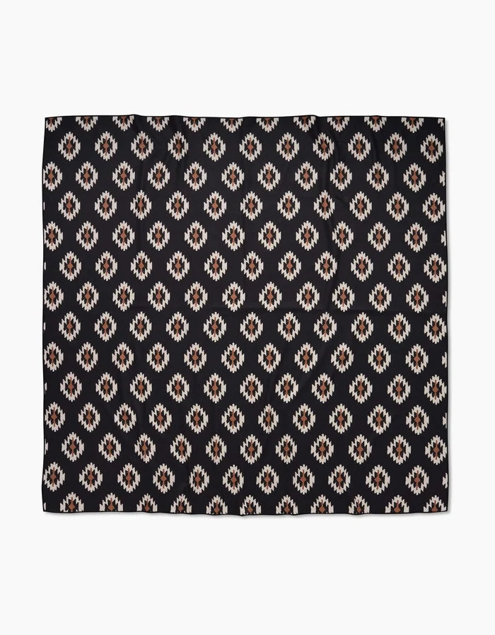 The Hufton Studio Western Tile Beach Blanket showcases a repeating geometric pattern with diamond motifs in white, tan, and brown on black, crafted from quick-drying recycled materials.