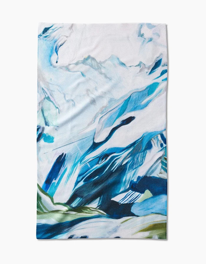The Where He Laid To Go tea towel by Kelly Peters features an abstract mountain landscape in blue, white, and green brushstrokes on Geoweave fabric, evoking snow-capped peaks and grassy areas.