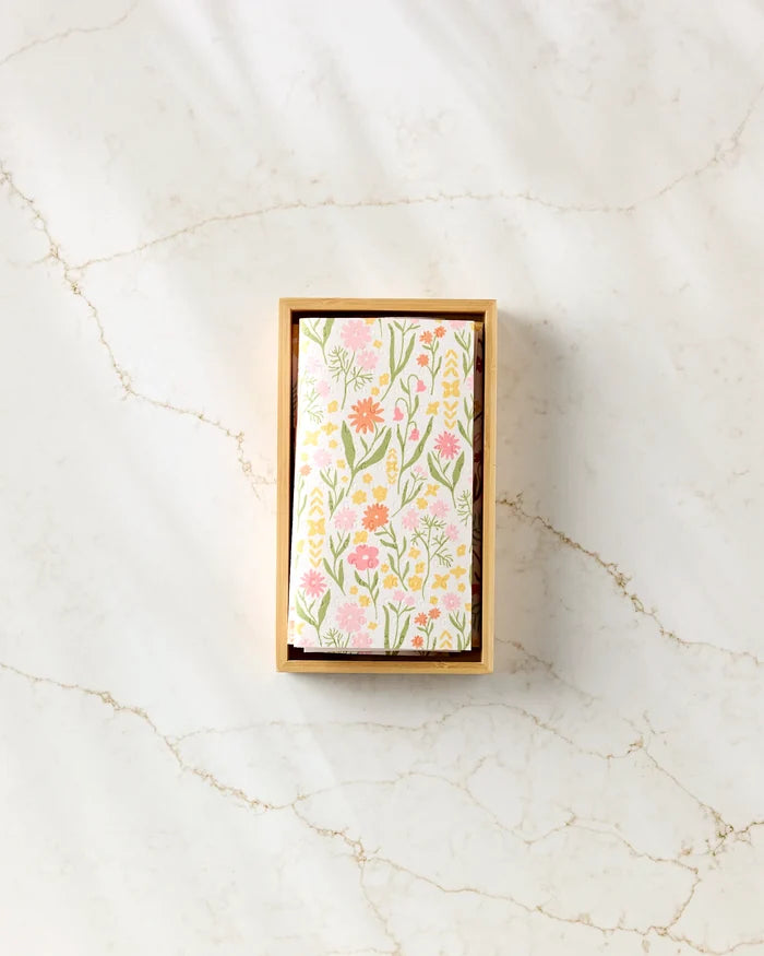 The Kayla Ann "Whimsy and Retro" reusable paper towels, featuring a floral pattern with pink, yellow, and green flowers on white, are displayed in a rectangular wooden box on a marble surface.