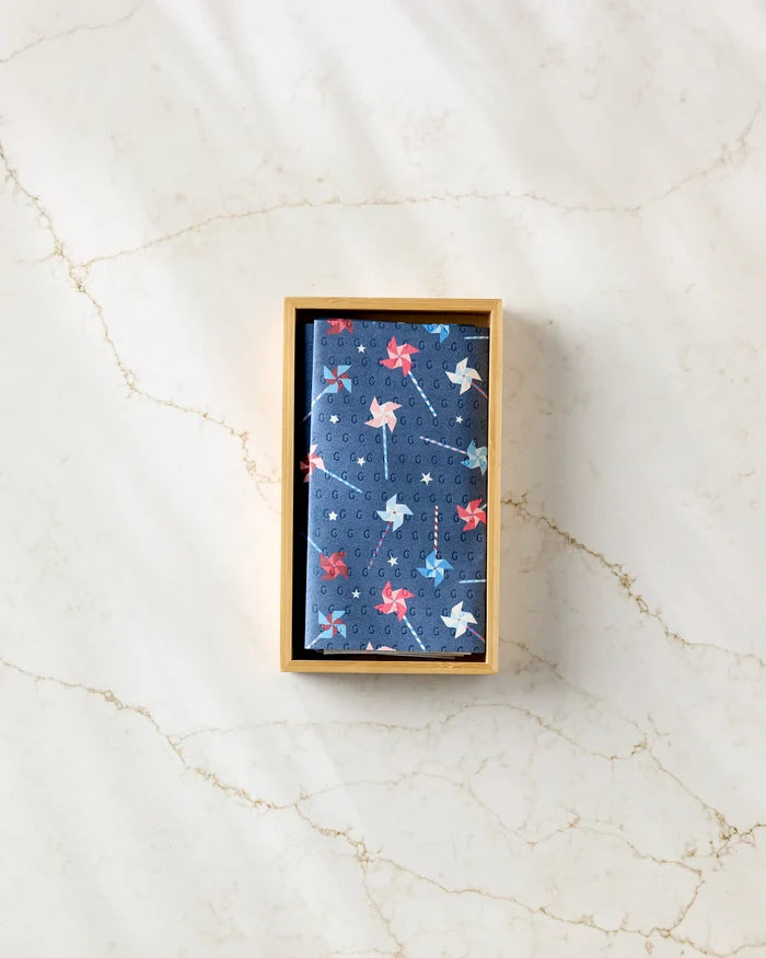 Whirlwind Pins by Rebecca Bobko: a folded blue handkerchief with a red, white, and blue airplane pattern in a tan box, offering a stylish, eco-friendly kitchen towel and reusable paper towel alternative.