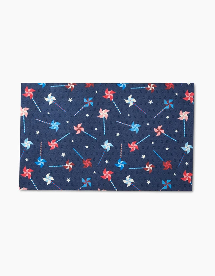 Whirlwind Pins by Rebecca Bobko is a rectangular, reusable mat with a dark blue background, red, white, and blue pinwheels, and small stars—an eco-friendly alternative to Not Paper Towels.