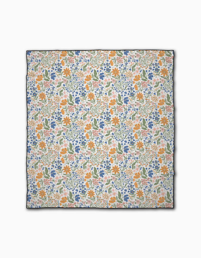 The Wildflower Vine Blush by Danelys Sidron is a square scarf with a vibrant orange, blue, and green floral print on white. Made from recycled materials, it features a thin dark border for an eco-friendly, chic finish.