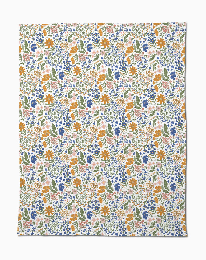 Wildflower Vine Blush by Danelys Sidron is a silky soft fabric with a vibrant floral pattern of small orange, blue, pink, and yellow flowers and green leaves densely scattered on a white background.