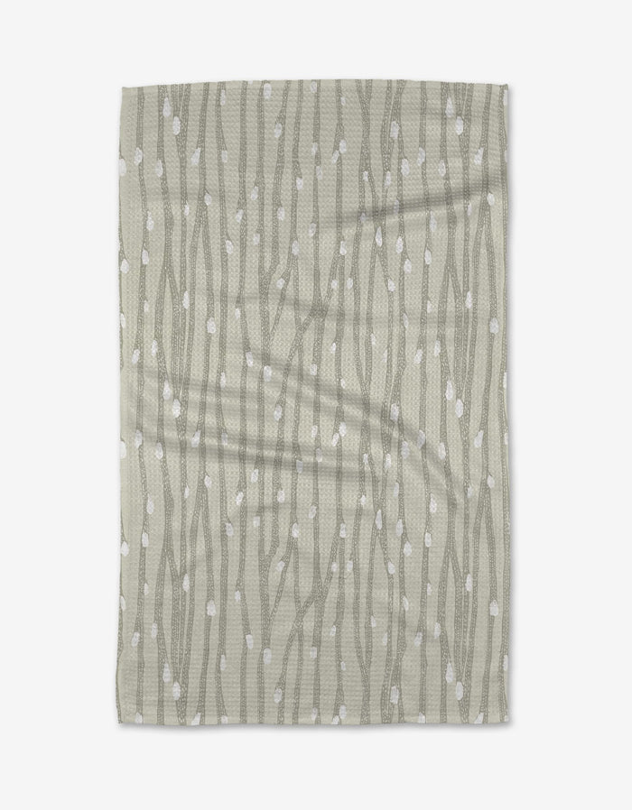 The Willow Branches tea towel by Katie OShea features a light gray background with vertical, wavy lines and scattered white dots, evoking the look of stylized branches or vines.