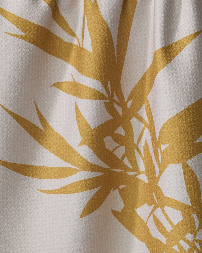 A close-up of PrintedPlant’s Willow tea towel in white, showcasing a bold, golden-yellow botanical pattern with overlapping leaves and stems.
