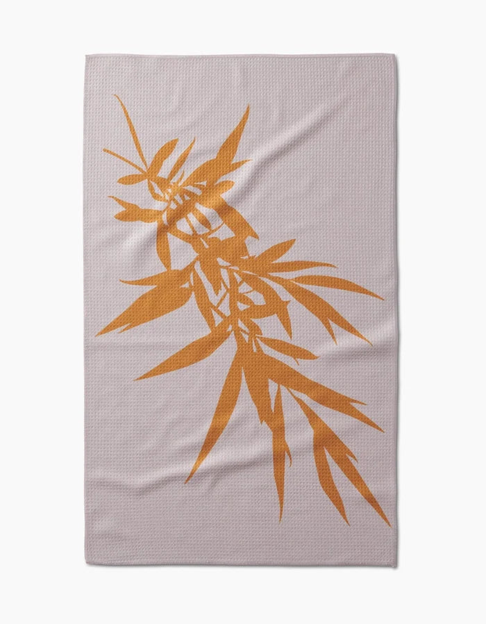 The Willow blanket by PrintedPlant features a large orange bamboo leaf design diagonally across light gray Geoweave fabric.