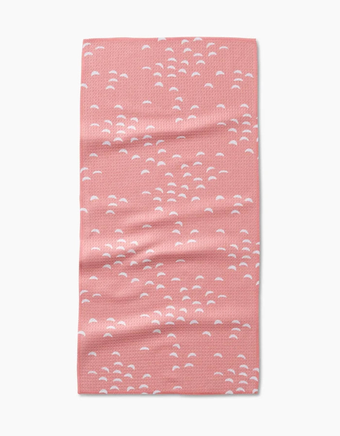 The “Windswept” bar towel by Jessica Swift is pink, rectangular, and made from Geoweave fabric. It features a scattered small white semi-circle pattern and is shown flat on a white background.