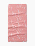 The “Windswept” bar towel by Jessica Swift is pink, rectangular, and made from Geoweave fabric. It features a scattered small white semi-circle pattern and is shown flat on a white background.