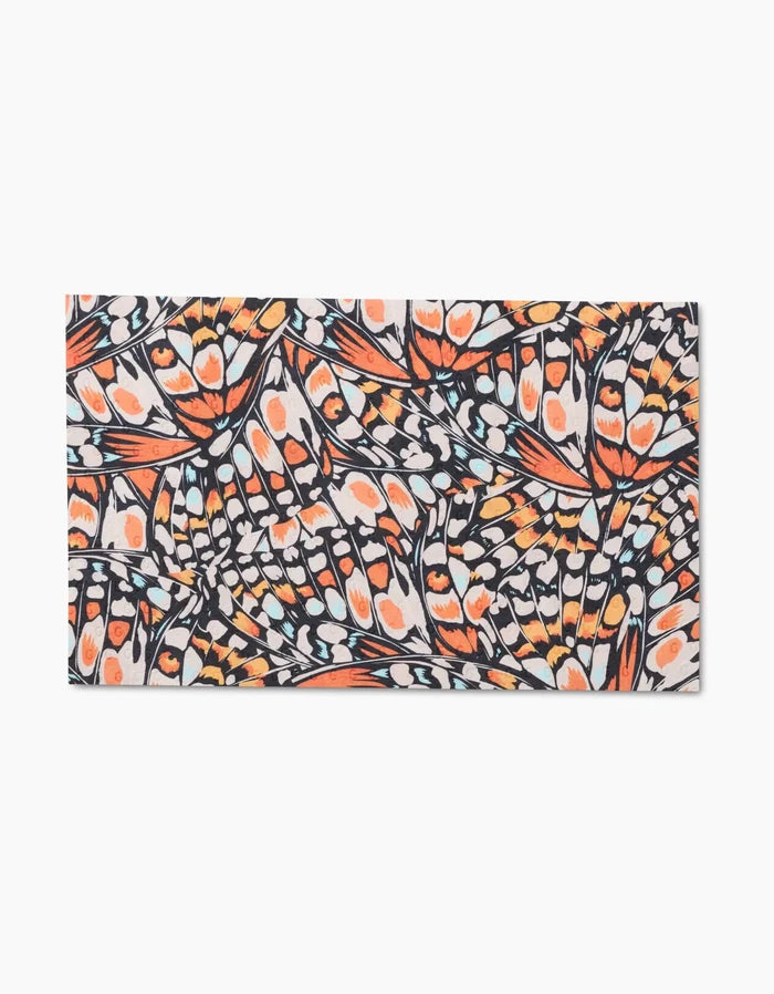 Wings in the Wind by GEOMETRY is an eco-friendly rectangular towel made from post-consumer recycled materials, featuring a dense, colorful abstract butterfly wing pattern in orange, black, white, and blue. Economical and sustainable—not paper towels.