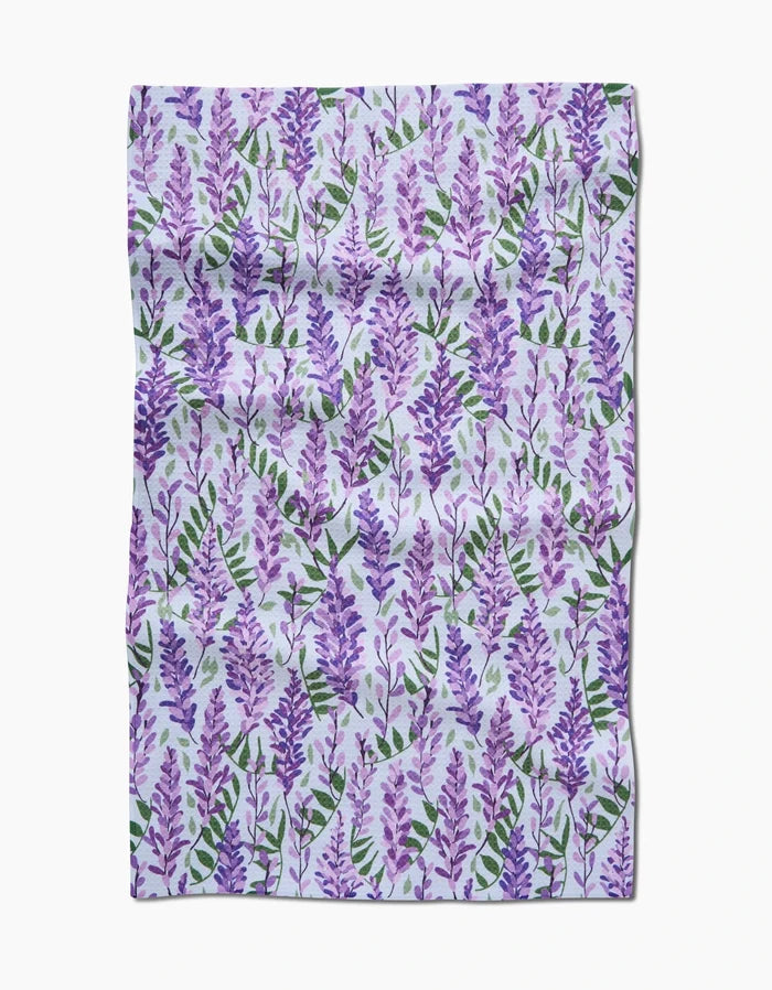 Wisteria by Rebecca Bobko is a rectangular, slightly wrinkled fabric made from recycled materials, featuring a repeating pattern of purple lavender flowers and green leaves on a light background.