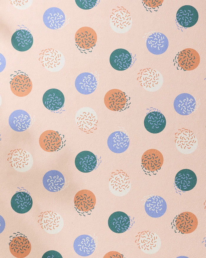 The Wonky Dots towel by Claire Iglesias features playful green, blue, orange, and cream circles with squiggly designs on light pink—perfect for adding whimsical charm to your recycled yoga accessory.