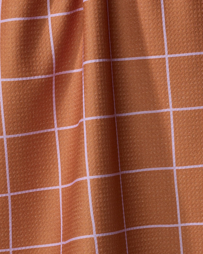 A close-up of Beetle Ink Co.'s Wonky Grid towel shows textured orange fabric with a white grid pattern. The wavy, ultra-absorbent surface creates gentle shadows and highlights.