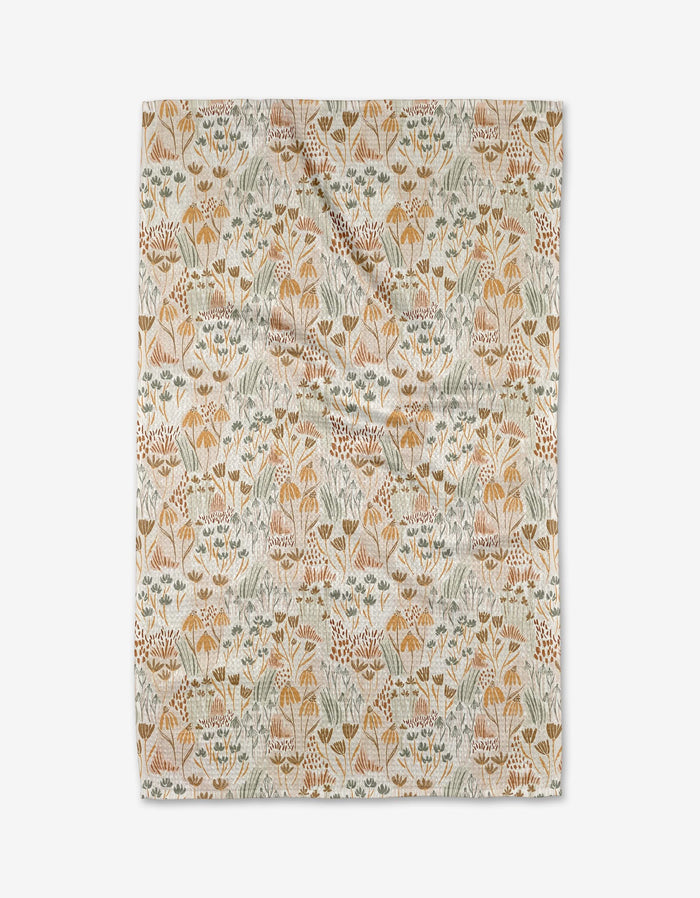 The Hufton Studio Woodland Floral tea towel features a rectangular Geoweave fabric with stylized flowers and leaves in muted yellow, orange, green, and blue on a cream background. It is shown laid flat with slight wrinkles.