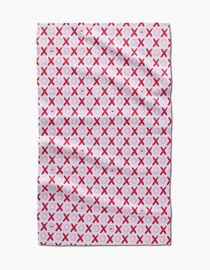 The XOXO towel by Sarah Daugherty is a rectangular, quick-drying towel with pink and red X and O letters in neat rows on a white background. It features a soft, absorbent texture and subtle fabric creases.