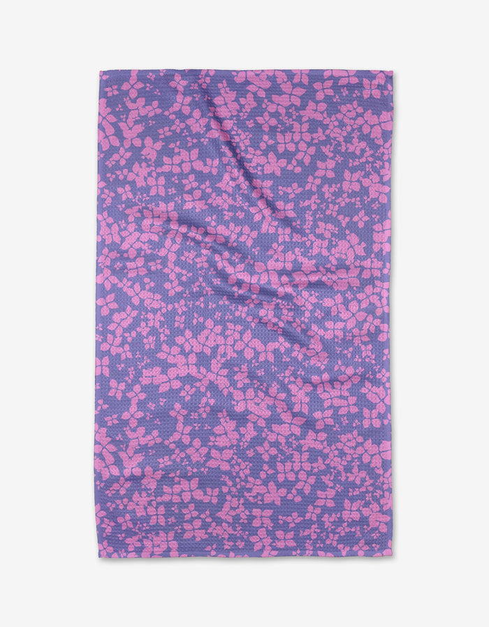 The Sareka Unique You Give Me Butterflies tea towel features a purple background with pink geometric shapes in a mosaic pattern. Made from Geoweave™ fabric, it has some wrinkles and is shown laid flat on a white surface.