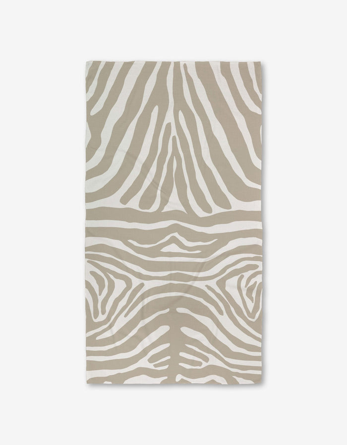 The GEOMETRY Zen Zebra bath towel, featuring a beige and white zebra stripe pattern and crafted with Geoweave technology for superior absorbency, is shown flat on a white background.