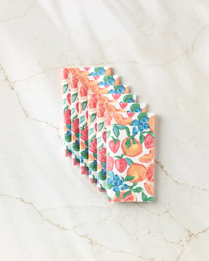 Six reusable Zesty Life paper towels by Aubrey Fairchild, each with vibrant orange, strawberry, and blueberry fruit patterns, are fanned out neatly on a white marble surface with light brown veining.