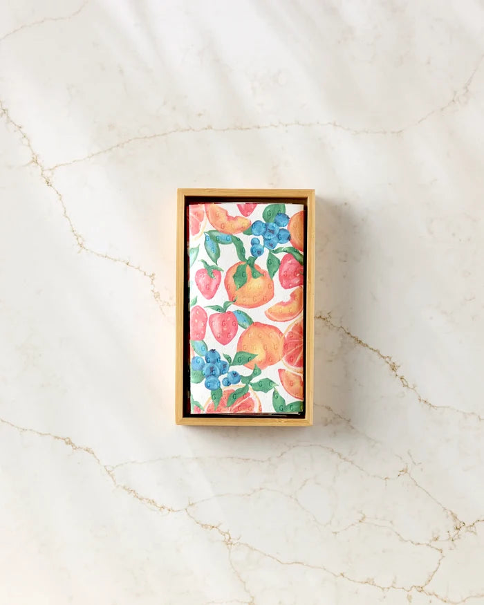 Aubrey Fairchild’s Zesty Life is a rectangular wooden box on marble, holding eco-friendly cards with colorful illustrations of strawberries, oranges, blueberries, and pears.