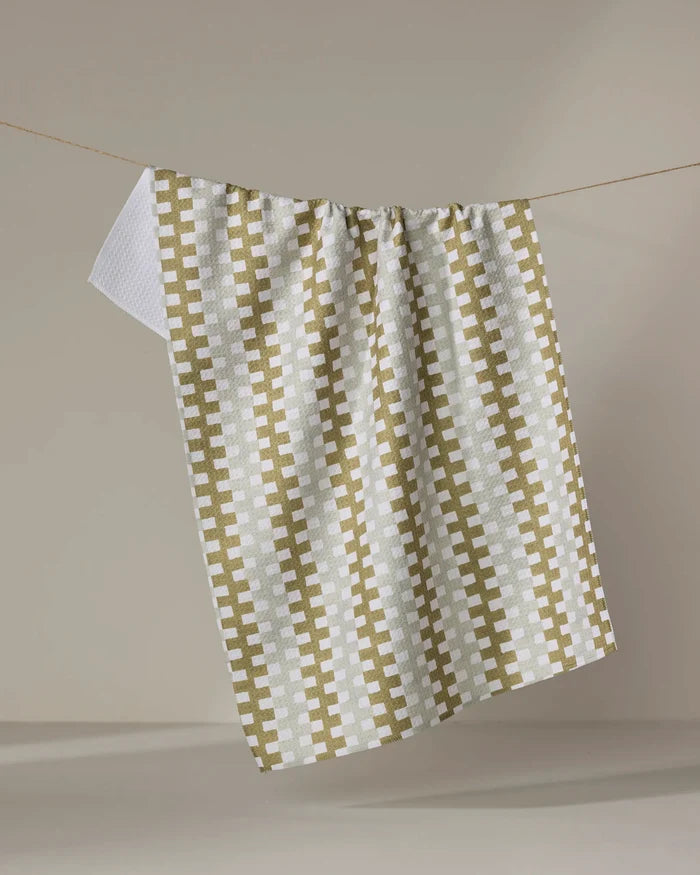 The Zippy tea towel by Studio Jeannot, featuring a green and white checkered design and made from quick-drying recycled materials, hangs on a string against a plain beige background.