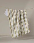 The Zippy tea towel by Studio Jeannot, featuring a green and white checkered design and made from quick-drying recycled materials, hangs on a string against a plain beige background.
